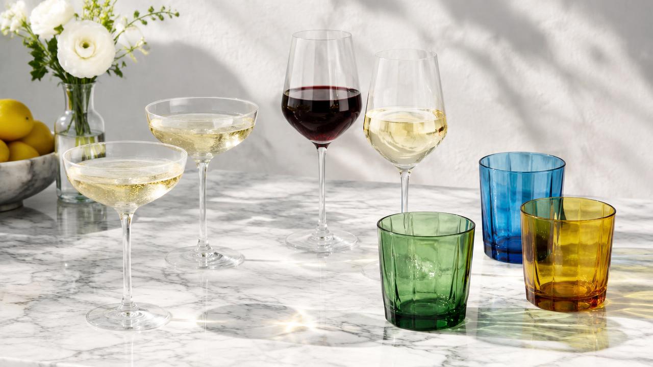 Champagne coupes, wine glasses and coloured tumblers on marble